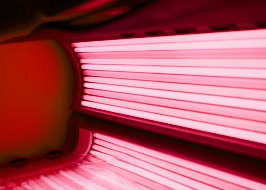 A powerful red light therapy panel emitting a bright red and near-infrared glow, used for full-body treatment and muscle recovery