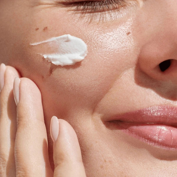 Woman applying moisturizer after red light therapy session – how to seal in LED results
